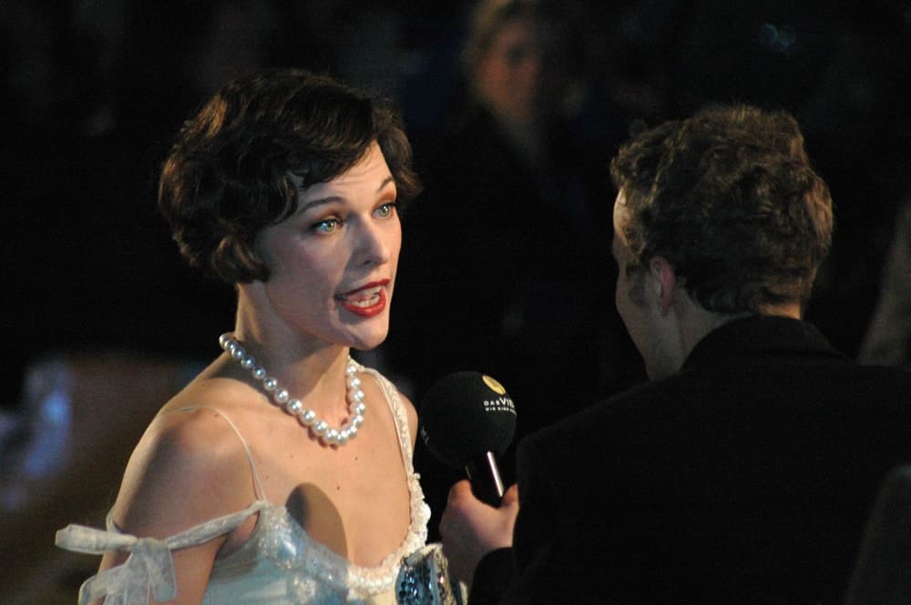 on February 13, 2006, Milla Jovovich was at the "Cinema for Peace Gala" in Gendarmenmarkt, Berlin. She wore a lovely pearl necklace with her white dress and raven curly pixie hairstyle that has a vintage finish to it.