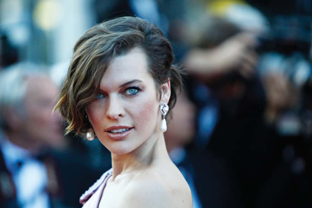 Mila Jovovich attended the 'On The Road' Premiere at Palais des Festivals on May 23, 2012 in Cannes, France. She was quite elegant in her pink dress and brunette bun hairstyle that has loose, side-swept and highlighted bangs.