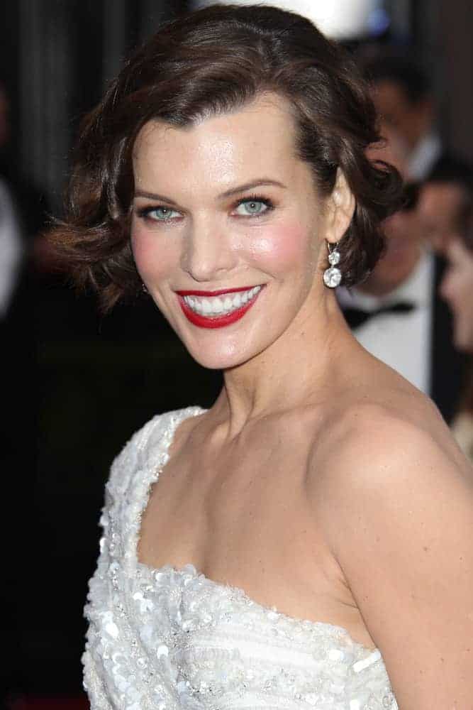 Milla Jovovich was at the 84th Academy Awards at the Hollywood & Highland Center on February 26, 2012, in Los Angeles, CA. She was lovely in a white dress, red lips, and tousled chin-length hairstyle with side-swept wavy bangs.