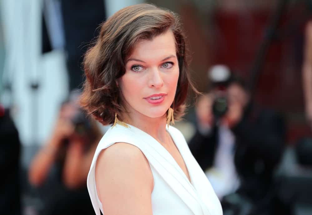 Milla Jovovich attended the 'Cymbeline' Premiere during the 71st Venice Film Festival at Sala Grande on September 03, 2014 in Venice, Italy. She paired her elegant white outfit with a shoulder-length tousled brunette hairstyle that has subtle waves and highlights.