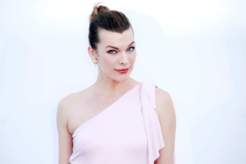Milla Jovovich was at the amfAR Gala Cannes 2018 at Hotel du Cap-Eden-Roc on May 17, 2018 in Cap d'Antibes, France. She wore a white gown that she paired with her slicked-back bun hairstyle.