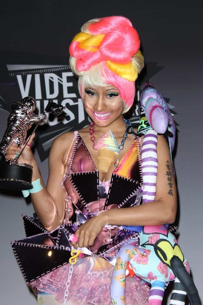 Nicki Minaj flaunted her hard-earned trophy at the 2011 MTV Video Music Awards Press Room in Nokia Theatre LA Live, Los Angeles, CA on August 28, 2011. She wore an artistic and colorful outfit that she paired with an equally colorful beehive bun hairstyle with bangs.