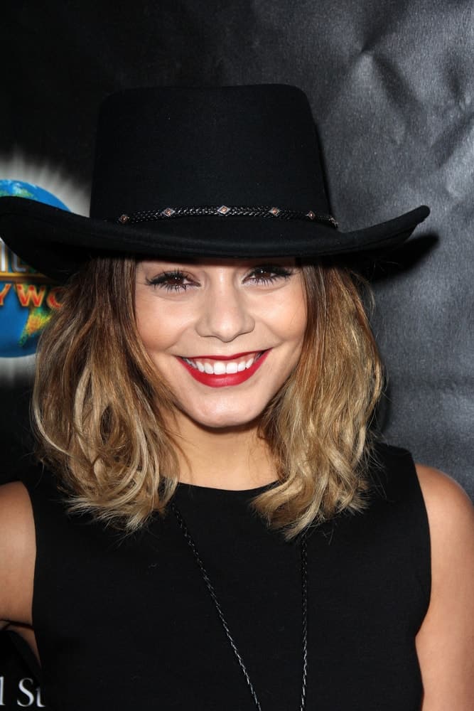 Vanessa Hudgens wore a simple black outfit with her black cowboy hat and shoulder-length highlighted hairstyle with a slight tousled finish at the Universal Studio's Halloween Horror Nights 2014 Eyegore Award at Universal Studios on September 18, 2014 in Los Angeles, CA.