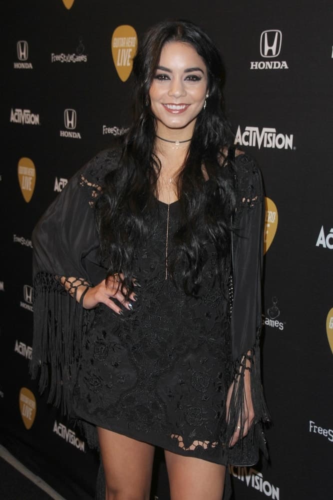 Vanessa Hudgens' short frilly black dress went quite well with her long and loose wavy hairstyle that has a slightly tousled finish at the Guitar Hero Live Launch Party at the YouTube Space LA on October 19, 2015 in Los Angeles, CA.