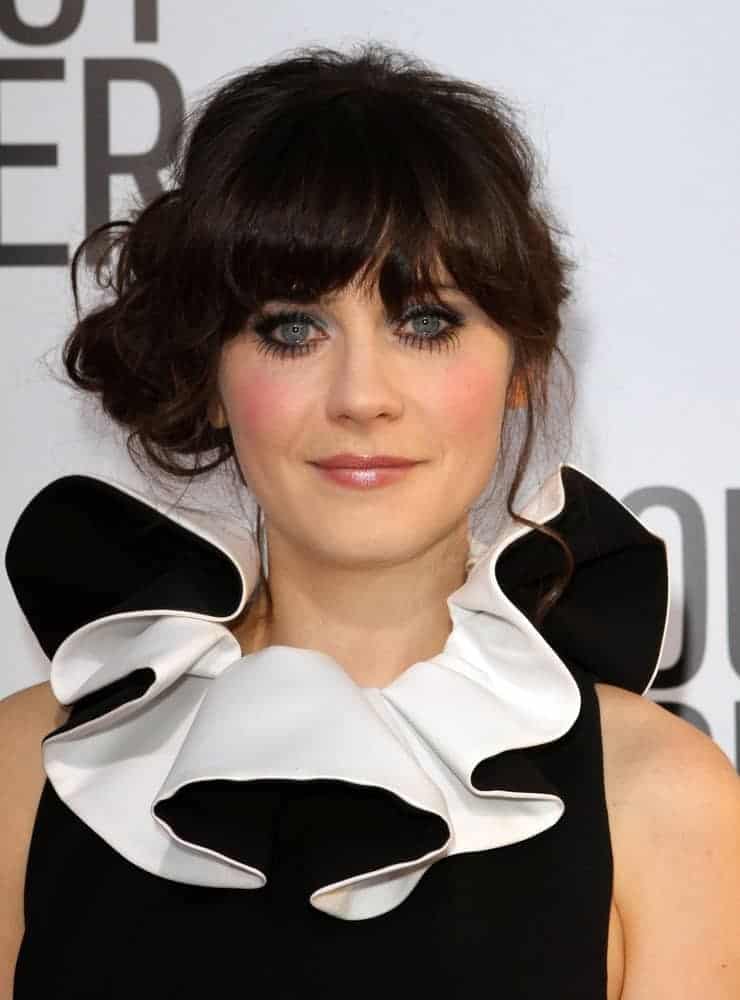 On August 16, 2011, Zooey Deschanel attended the "Our Idiot Brother" Los Angeles Premiere held at The Cinerama Dome in Hollywood, California. She wore a fashionable black and white dress to pair with her messy dark bun hairstyle with bangs and tendrils.