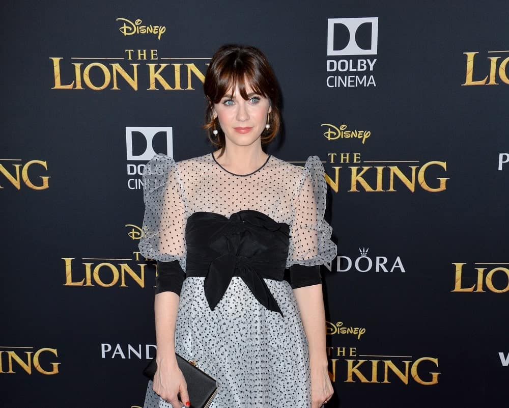 On July 10, 2019, Zooey Deschanel was at the world premiere of Disney's "The Lion King" at the Dolby Theatre. She wore a charming dress with her messy and loose brunette bun hairstyle that has bangs.