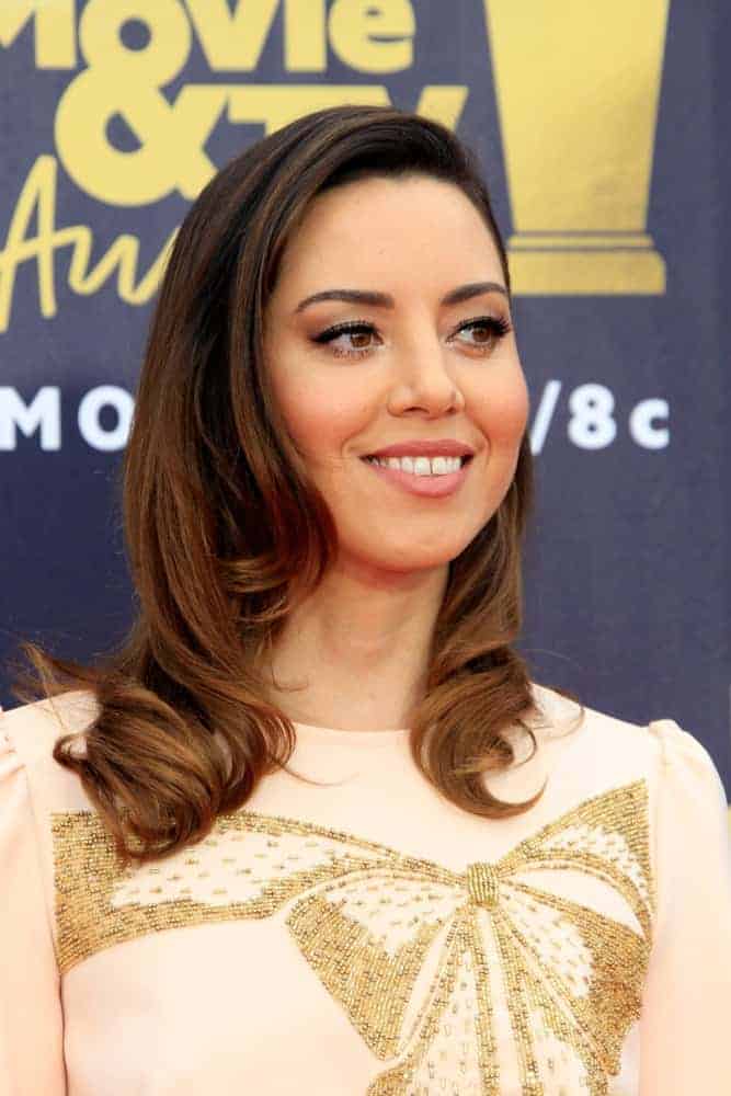 Aubrey Plaza was at the 2018 MTV Movie And TV Awards at the Barker Hangar on June 16, 2018, in Santa Monica, CA. She was charming in a gold-detailed dress that she paired with her medium-length brunette hairstyle with spiral curls and layers.