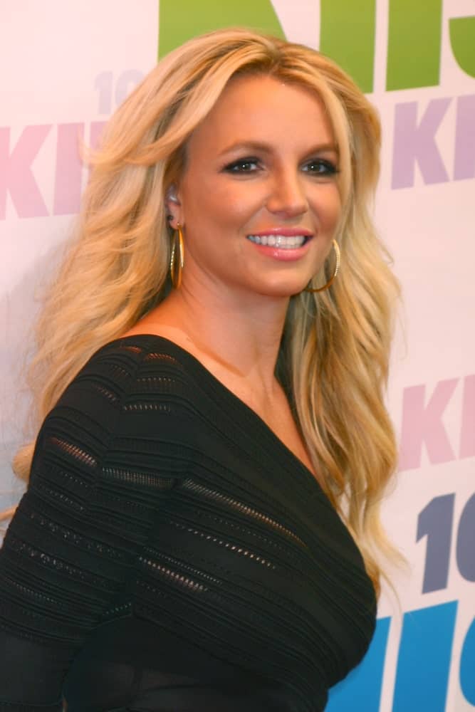 Britney Spears contrasted her blonde wavy hair with a one-shoulder black dress that was worn at the 2013 Wango Tango concert produced by KIIS-FM on May 11, 2013.
