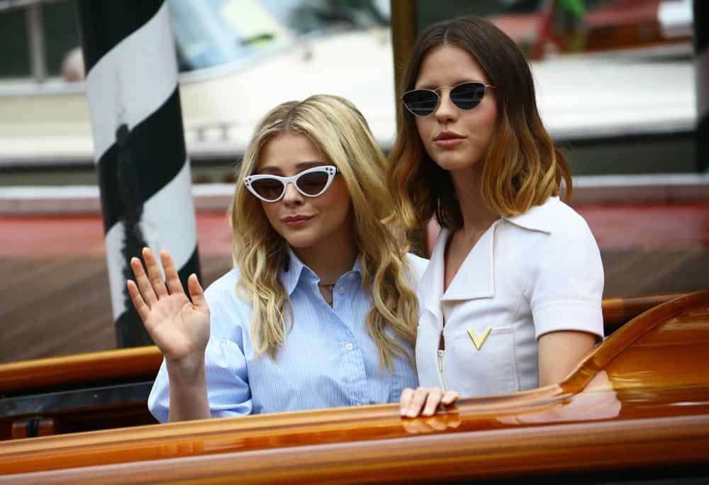 Chloe Grace Moretz and Mia Goth were seen waving at the fans during the 75th Venice Film Festival on September 1, 2018 in Venice, Italy. Moretz was wearing a casual outfit with a pair of cat-eye sunglasses and tousled wavy sandy blonde hairstyle.