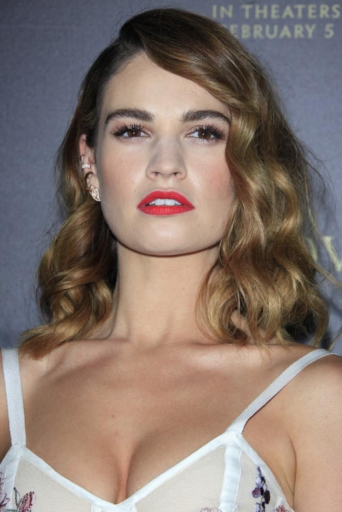 Lily James was at the Pride And Prejudice And Zombies Premiere at the Harmony Gold Theatre on January 21, 2016 in Los Angeles, CA. She was charming in a white dress that she paired with red lips and curly brunette shoulder-length hairstyle with side-swept bangs.