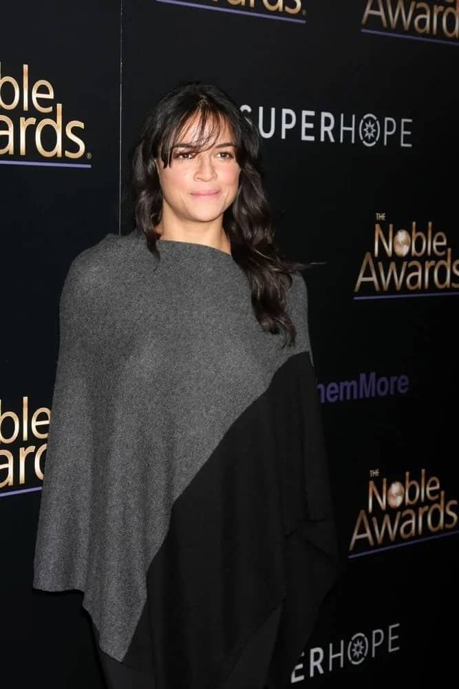 Michelle Rodriguez went fancy in a black and gray knit poncho paired with a baggy black jumper. She matched this comfy look with pretty loose curls with a spot of fringe as she attends the Noble Awards on February 27, 2015. 
