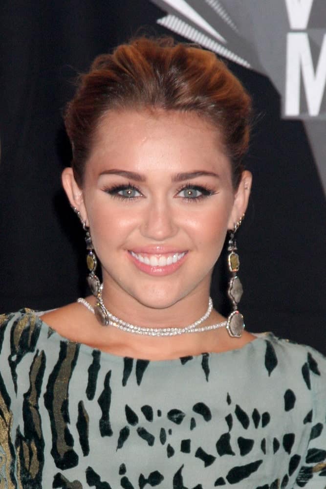 Miley Cyrus wore an animal print gray dress that she paired with a messy bun hairstyle to emphasize her lovely eyes and earrings at the 2011 MTV Video Music Awards at the LA Live on August 28, 2011 in Los Angeles, CA.