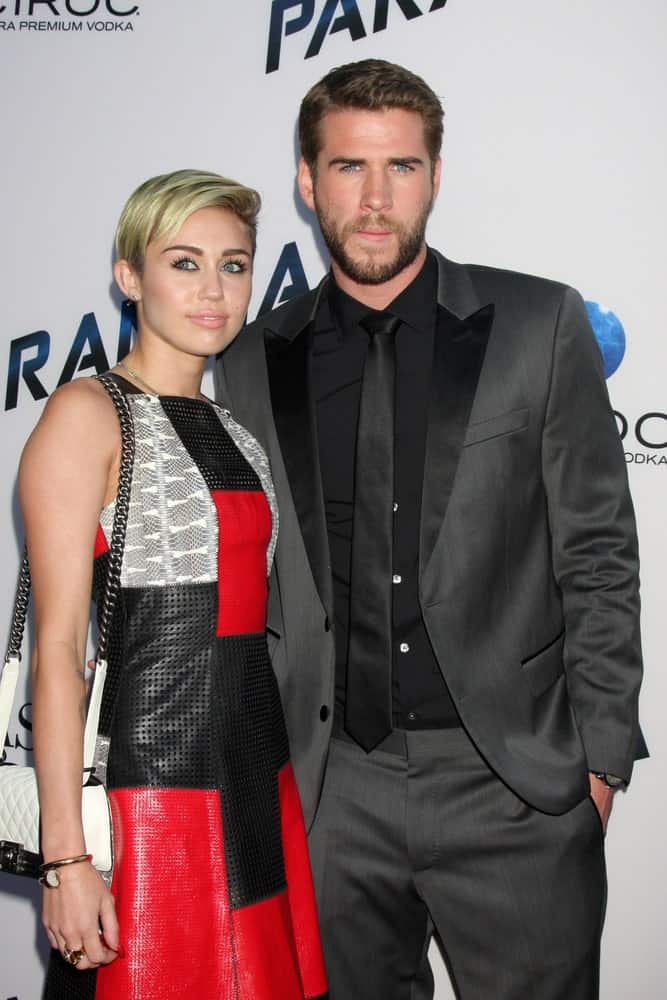 Miley Cyrus and Liam Hemsworth were at the "Paranoia" Los Angeles Premiere at the Directors Guild of America on August 8, 2013 in Los Angeles, CA. Cyrus wore a lovely colorful patterned dress that complemented her side-swept sandy blond pixie hairstyle.