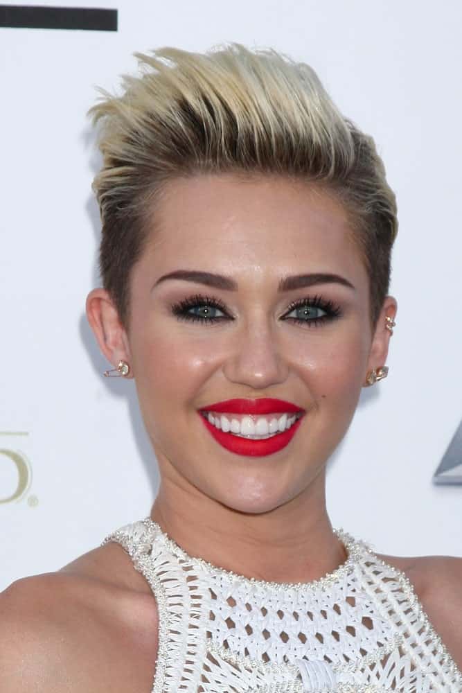 Miley Cyrus sported a white outfit that she paired with bold red lips and her spiked highlighted fade hairstyle at the Billboard Music Awards 2013 at the MGM Grand Garden Arena on May 19, 2013 in Las Vegas, NV.