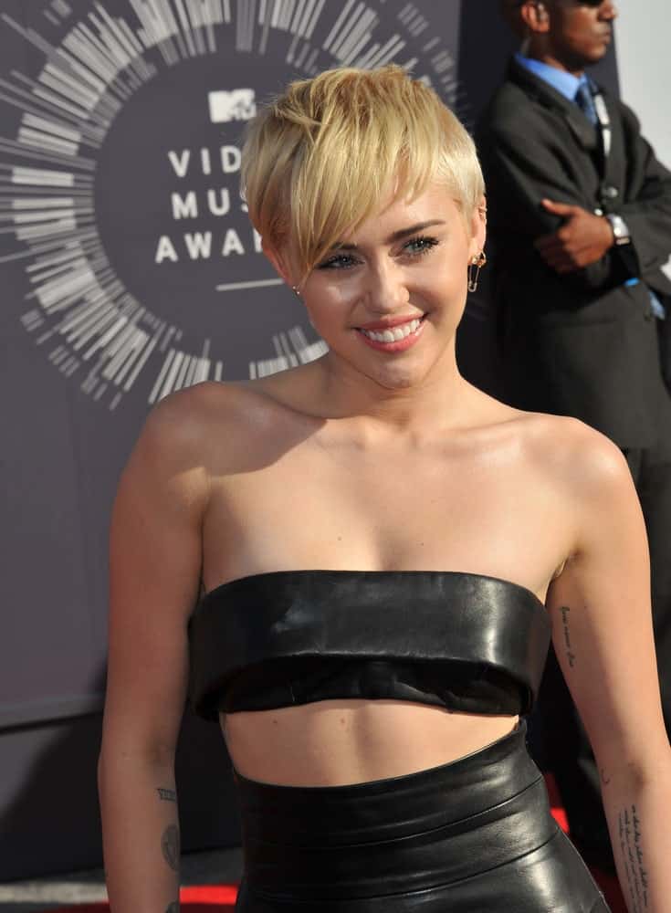 On August 24, 2014, Miley Cyrus attended the 2014 MTV Video Music Awards at the Forum, Los Angeles. She wore a sexy two piece black leather outfit that she paired with a sandy blond side-parted hairstyle.