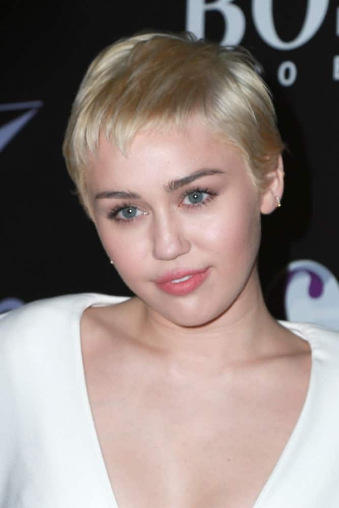 Miley Cyrus paired her white outfit with her platinum blond soft and loose pixie hairstyle at the W Magazine's Shooting Stars Exhibit at the Old May Company Building on January 9, 2015 in Los Angeles, CA.
