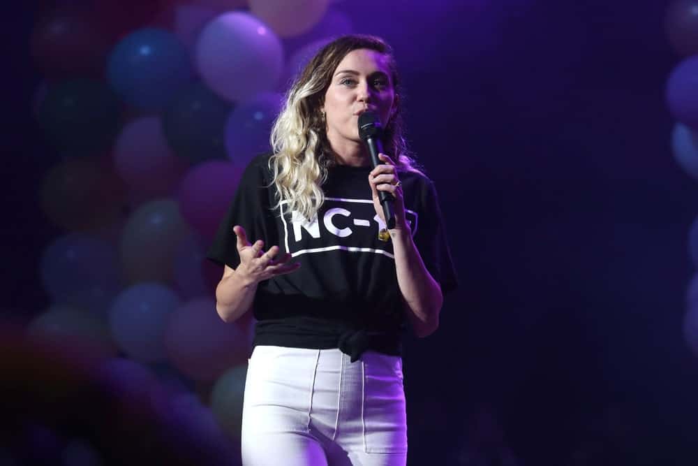 Miley Cyrus wore a simple black shirt with her long side-swept wavy balayage hairstyle when she performed during the Summer Jam concert at the Jones Beach Theater on June 16, 2017 in New York.