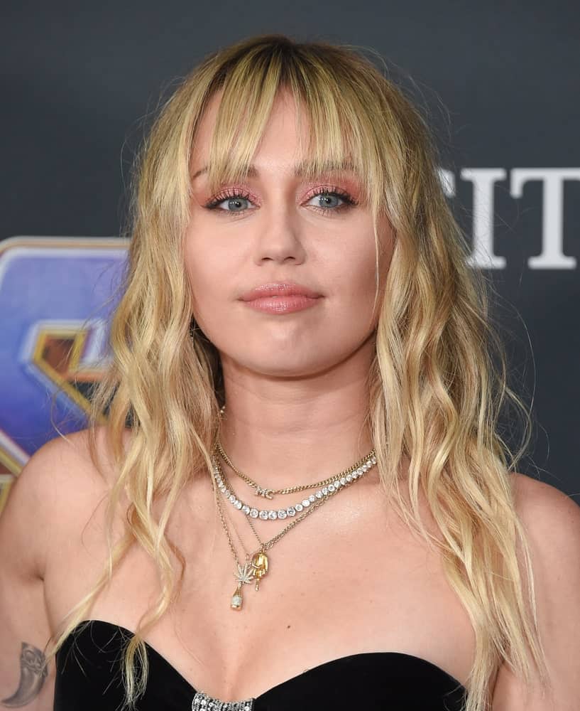 Miley Cyrus attended the "Avengers: End Game" Los Angeles Premiere on April 22, 2019 in Los Angeles, CA. She wore a classy black strapless gown that she paired with her medium-length wavy and tousled blond hair with eye skimmer bangs.