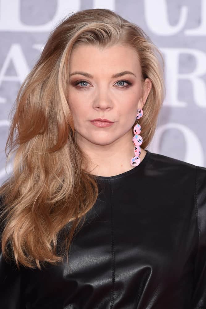 Natalie Dormer with her voluminous blonde tresses styled in side-swept layers. This hairstyle along with a black leather dress was worn during the BRIT Awards 2019 at the O2 Arena, London on February 20th.