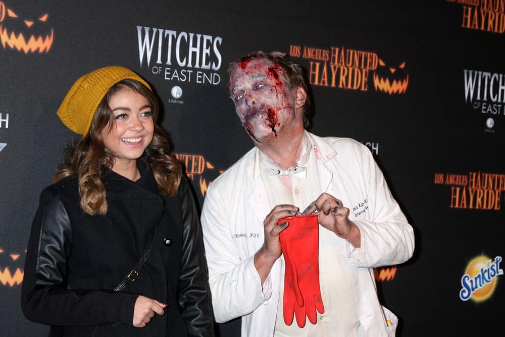Sarah Hyland was at the 8th Annual LA Haunted Hayride Premiere Night at Griffith Park on October 10, 2013 in Los Angeles, CA. She wore a winter jacket and a beanie over her long brunette hair with layers and curls.
