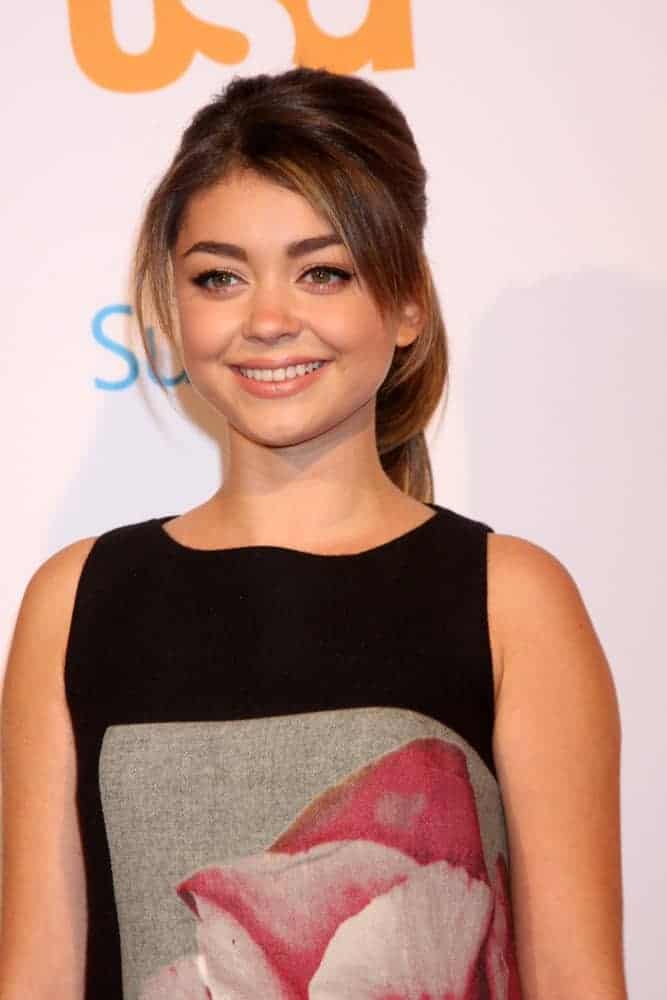Sarah Hyland was at the Modern Family on USA Network Fan Appreciation Event at Village Theater on October 28, 2013, in Westwood, CA. She wore a simple yet lovely black dress that she paired with a highlighted ponytail hairstyle with loose bangs.