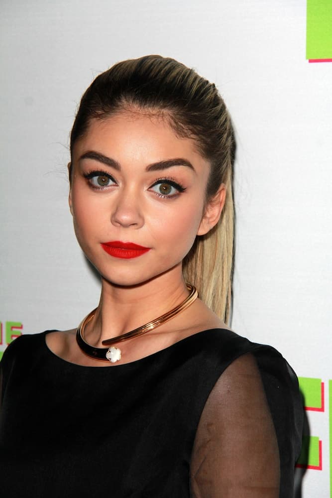 Sarah Hyland was at the "The Duff" Los Angeles Premiere at the TCL Chinese 6 Theaters on February 12, 2015 in Los Angeles, CA. She wore a black dress with her red lipstick and slicked back highlighted ponytail hairstyle.