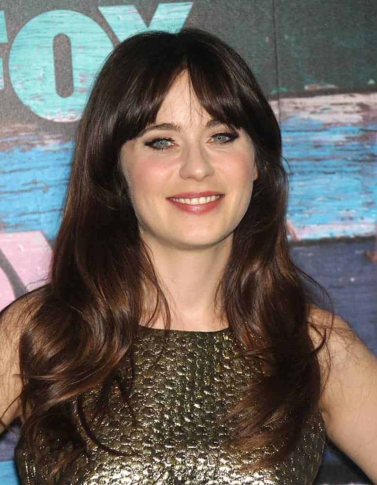 Zooey Deschanel attended the FOX All-Star Party 2012 on July 23, 2012, in West Hollywood, CA. She paired her metallic dress with a long and wavy tousled dark brunette hairstyle with long bangs and layers.