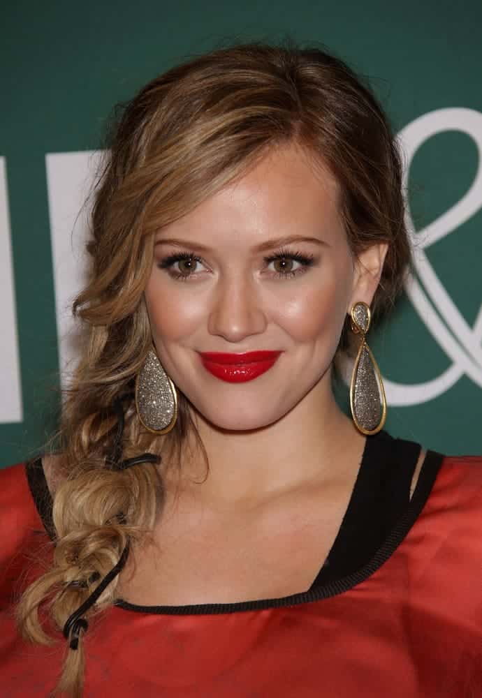 She's wearing an interesting fishtail side braid for with feathered bangs her blonde waves as she signs for 'Devoted' on October 14, 2011.