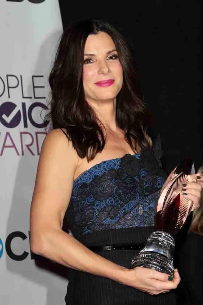 Sandra Bullock went with a carefree and gorgeous loose layered waves with a center part when she accepted her award at the 2013 People's Choice Awards Press Room back in January 9, 2013.