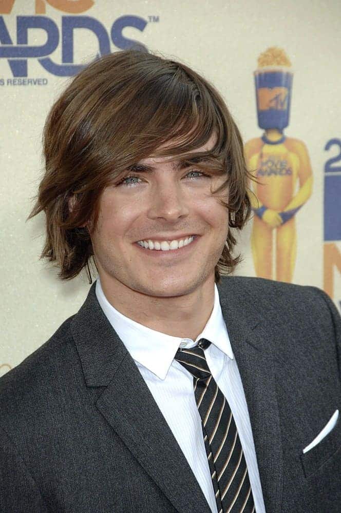 Zac Efron flashed a sweet smile with his long tousled locks styled with side-swept bangs at the 2009 MTV Movie Awards held on May 31, 2009. He wore a gray suit paired with a black striped tie.