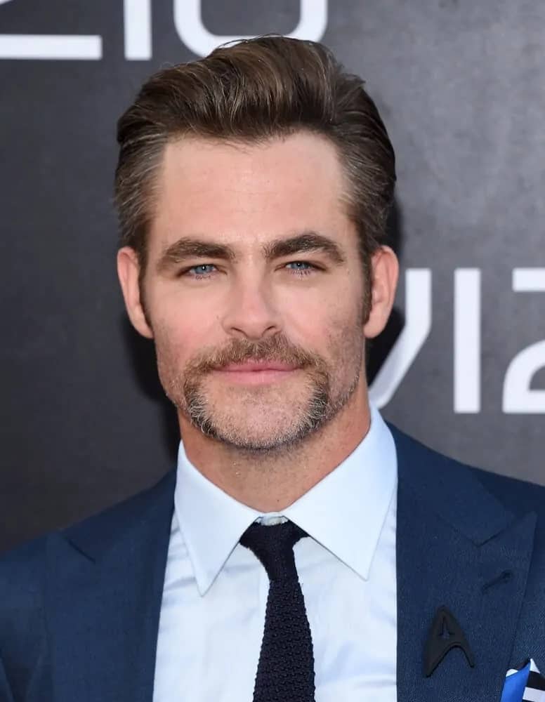 Chris Pine wore a salt and pepper pompadour hairstyle and a Star Trek pin on his blue suit when he attended the "Star Trek Beyond" U.S. 2016 Premiere in San Diego, California.
