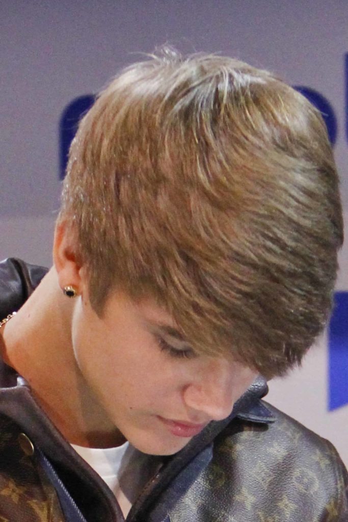 Singer Justin Bieber bows down his head, giving a full view of his signature hairstyle at the mRobo booth at the Consumer Electronics Show at The Las Vegas Convention Center in Las Vegas, NV on January 11, 2012.