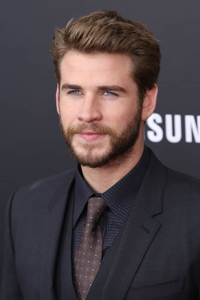 Liam Hemsworth attending the premiere of "The Hunger Games: Mockingjay - Part 2" at AMC Lincoln Square in New York City with a typical college boy hairstyle.
