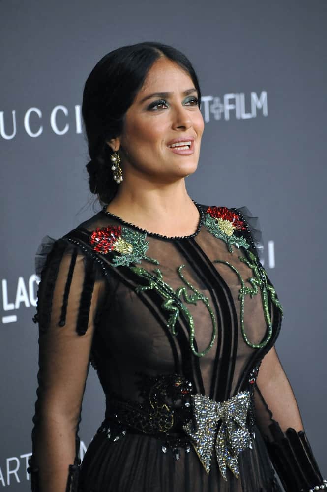 Actress Salma Hayek Pinault was at the October 29, 2016 LACMA Art+Film Gala at the Los Angeles County Museum of Art. She had her hair styled to a classy low bun to match her black dress with shiny details.