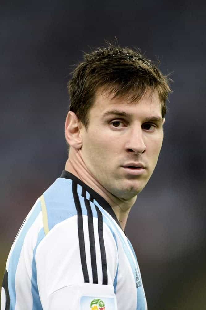 On June 15, 2014, Lionel Messi of Argentina played during the 2014 World Cup when Argentina is facing Bosnia in Group F at Maracana Stadium in Rio, Brazil. He paired his white uniform with a clean-shaven face and a short fringe hairstyle.