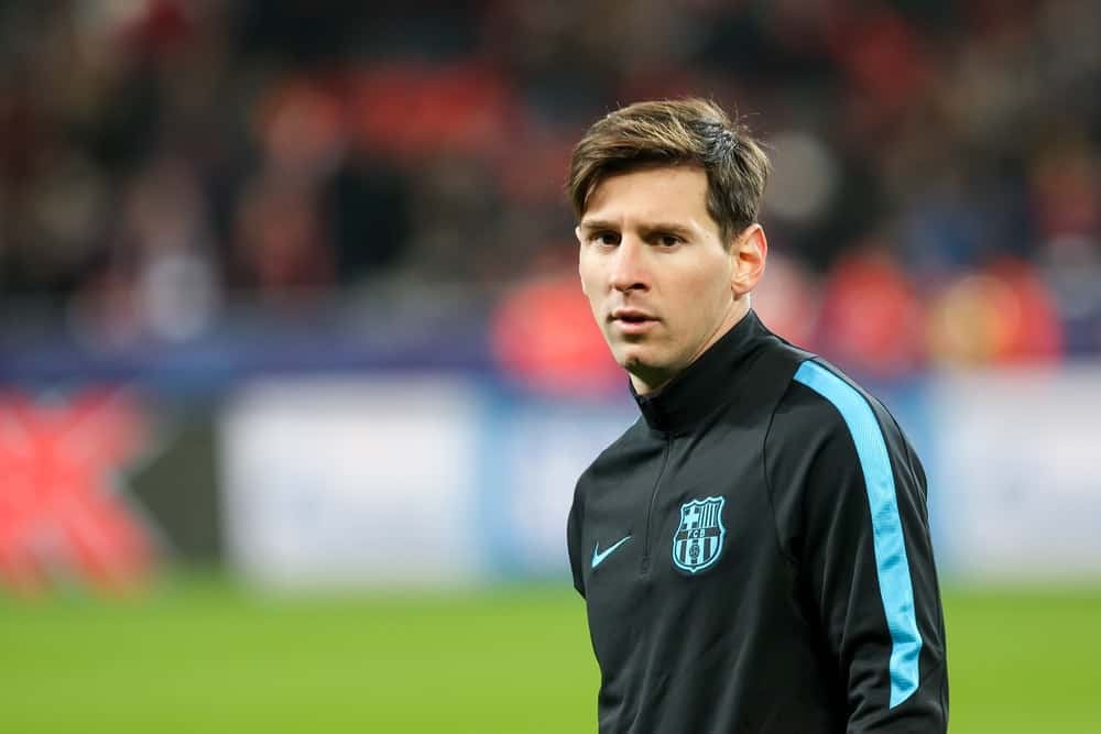 On December 9, 2015, Lionel Messi warmed up before the UEFA Champions League game between Bayer 04 Leverkusen vs Barcelona at BayArena Stadium in Leverkusen, Germany. He wore a jacket with his medium-length side-parted dark brown hairstyle.
