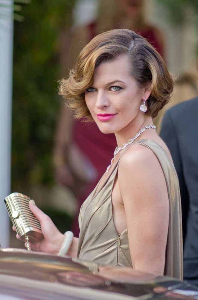 Actress and model Milla Jovovich were seen leaving Hotel Martinez during the 64th Annual Cannes Film Festival on May 19, 2011, in Cannes, France. She wore a golden dress that pairs well with her chin-length wavy brunette hairstyle with long side-swept bangs.