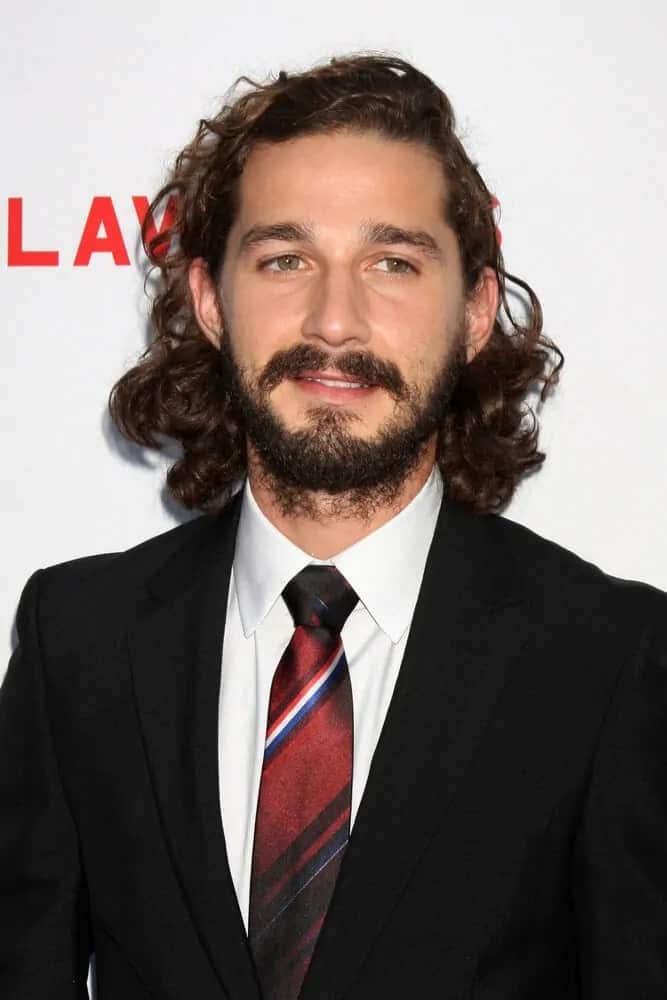 Shia LaBeouf had mid-length dark brown curly hair effortlessly left tousled for a grunge look last August 22, 2012 for the LA premiere of "Lawless".