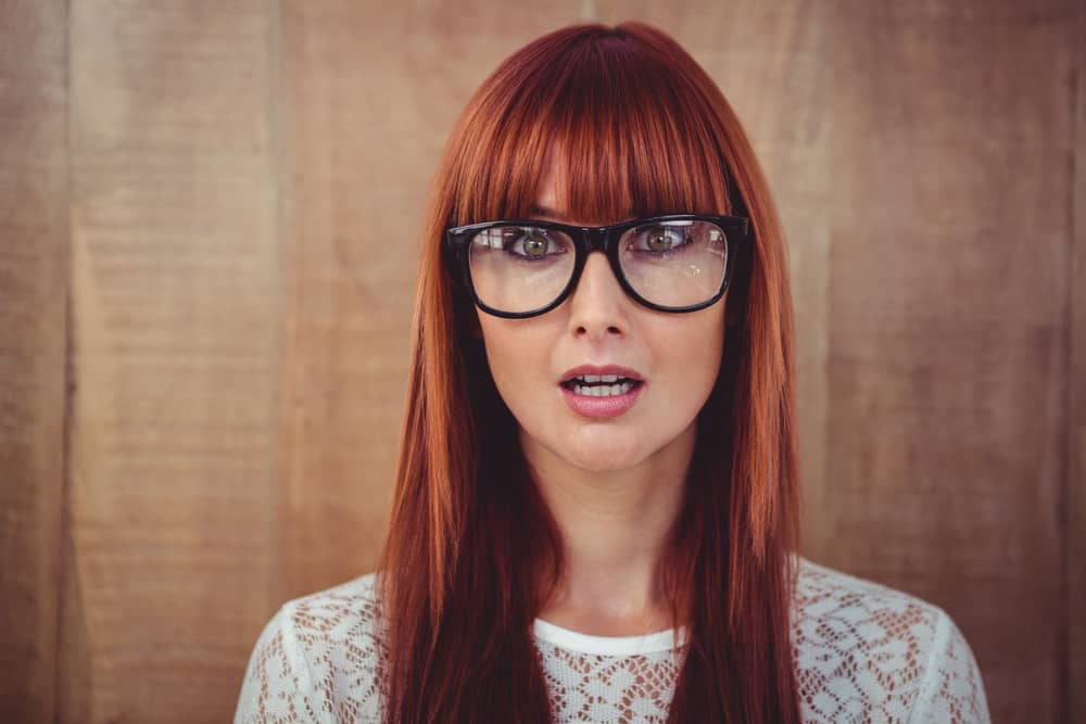 Woman with long straight red hair and blunt bangs (and glasses)