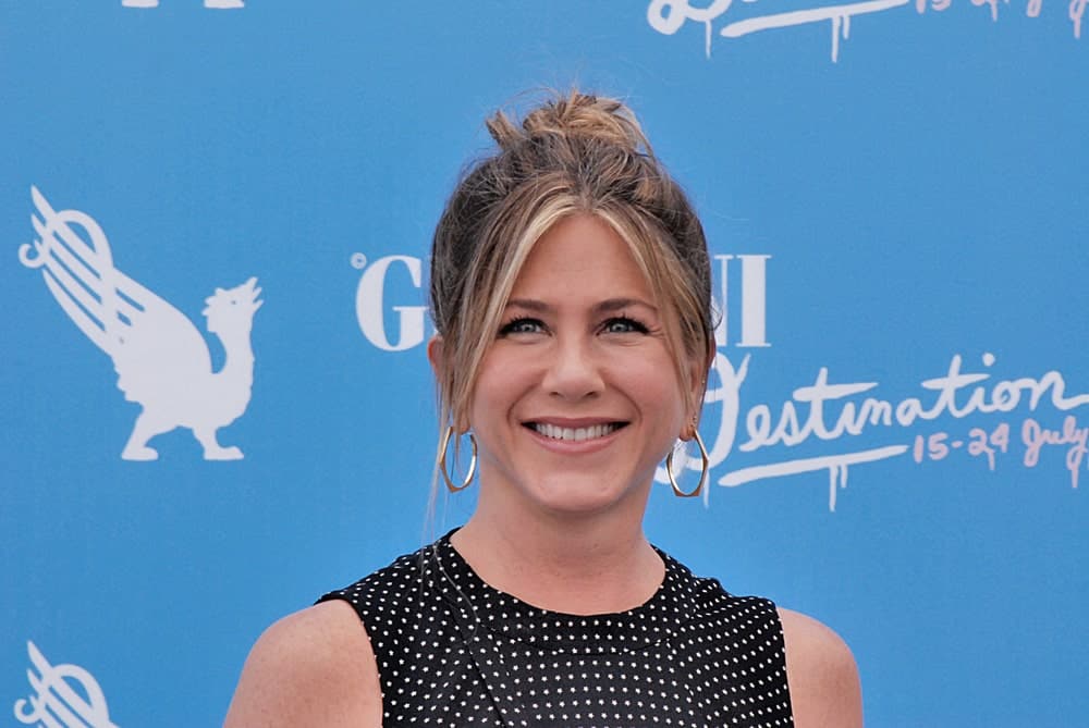 Jennifer Aniston showcased a messy bun hairstyle with curtain bangs at Giffoni Film Festival 2016 held on July 23rd. Gold hoop earrings and a black dotted dress completed the gorgeous look.