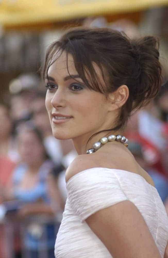 Keira Knightley was at the world premiere of her new movie Pirates of the Caribbean: The Curse of the Black Pearl, at Disneyland, California on June 28, 2003. She came in a messy dark bun hairstyle with loose tendrils and bangs.