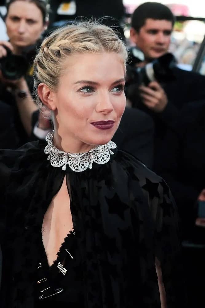 Sienna Miller made a surprising appearance in a black semi-sheer gown featuring a dramatic cape. Her double braid bun hairstyle complements her elegant outfit during the 'Carol' premiere held on May 17, 2015.