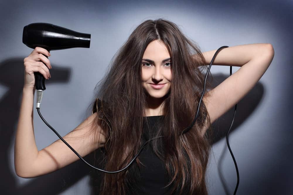 Gorgeous woman blow drying her hair.