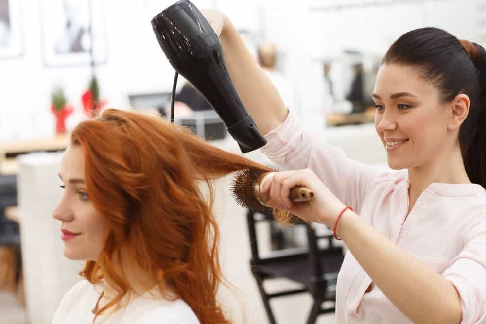Ginger-haired woman getting a blow dry from her stylist.