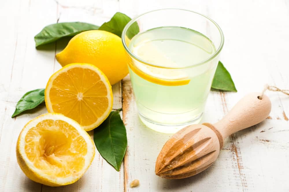 Lemon juice on a glasses with fresh lemons on the side.