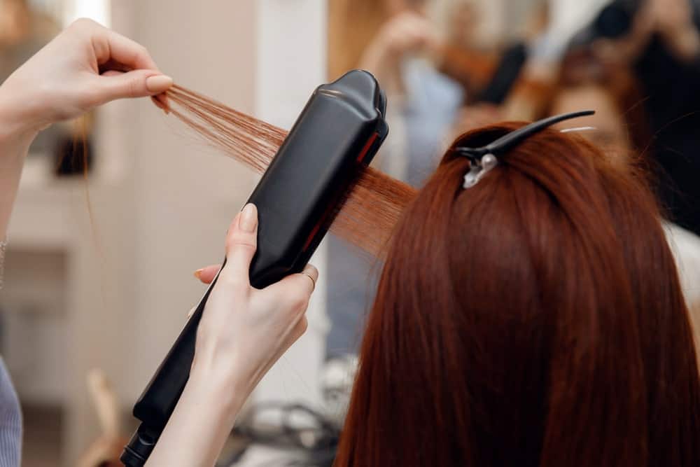 Stylist relaxing a ginger hair woman.