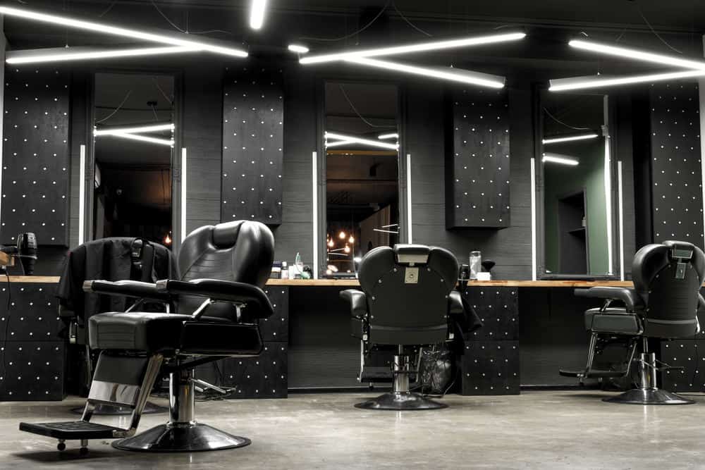 Here's a modern barber shop design. It's very masculine with the black walls and chairs. Check out the Star Wars like lighting. This is definitely a unique barber shop interior look that works well. It's a big difference from the rustic and vintage looking barber shops you so often see.