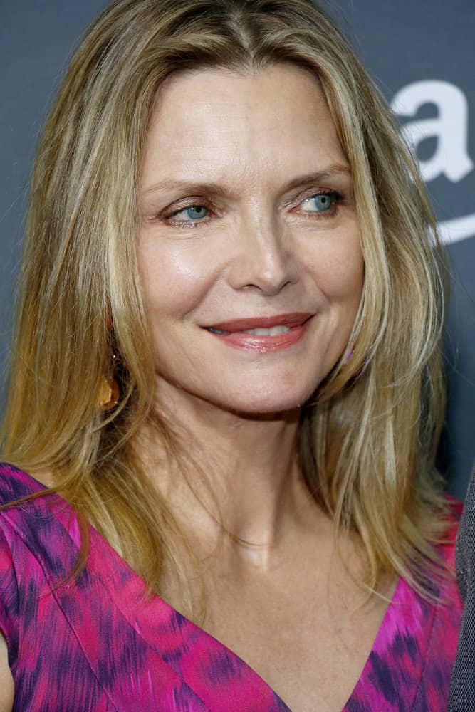 This sixth, simple, but effective hairstyle is modeled by Michelle Pfeiffer. The long-layered style features a light blonde color, with slivers of silver highlights. Along with the long and gently curled layers of hair, a middle part is featured. 