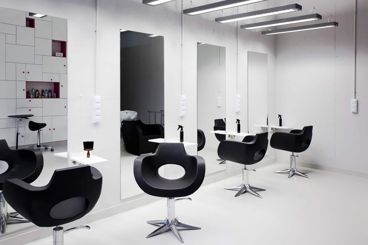The sharp contrast between black and white paired with the polished look of stainless steel gives this salon a sleek and stylish look. Add some large mirrors, fluorescent lighting, and red accents for a contemporary feel. The glossy red shelves and knobs on the white wall shelf pop and the black seating and the spray bottles on the white floating shelves. 
