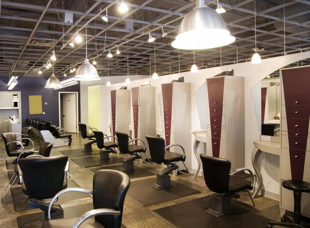 Numerous hanging stainless steel pendant lights brighten up this salon and highlight the black and stainless steel chairs. The Medium blue walls accent the maroon chevron stripe painted on the drawers with stainless steel knobs. 